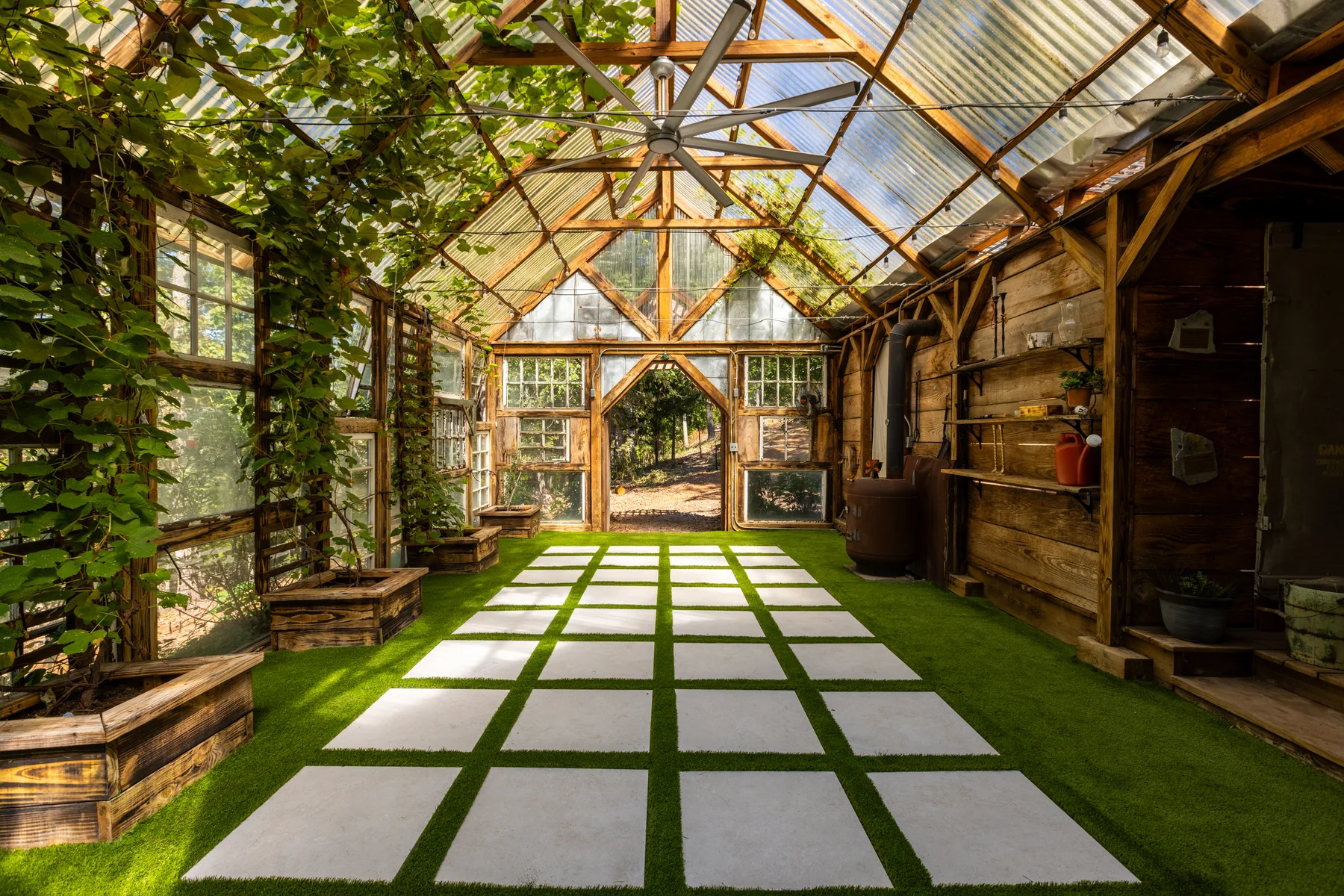 Square-grid PaverTurf floor inside a wood-framed greenhouse