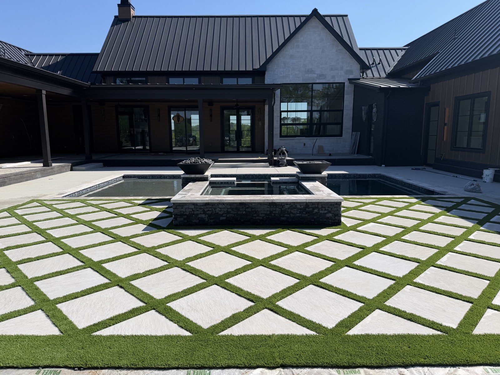 Completed PaverTurf pool deck with a diamond grid of light pavers and green turf